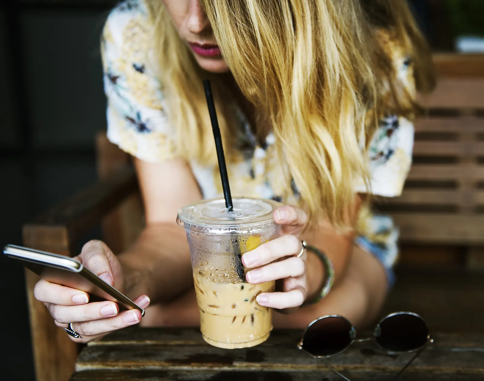 Quelqu’un réserve sur son téléphone, un café glacé à la main.