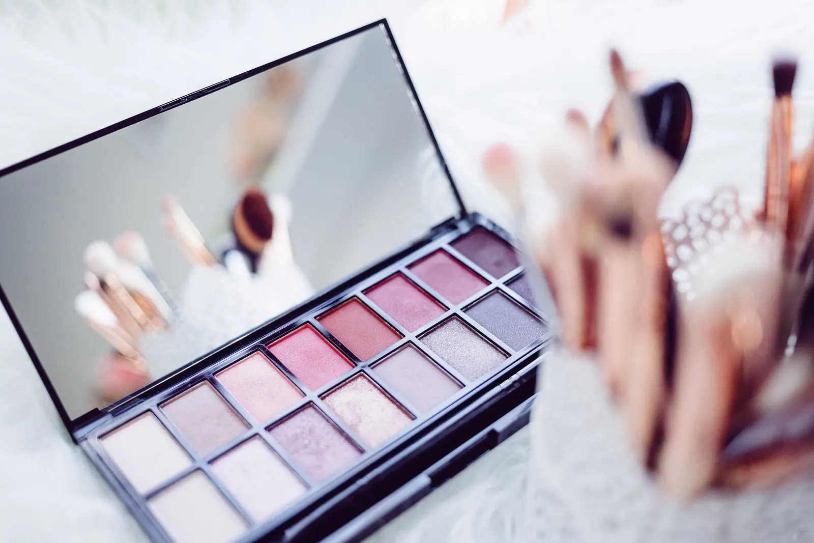 Une palette de fards et des pinceaux de maquillage.