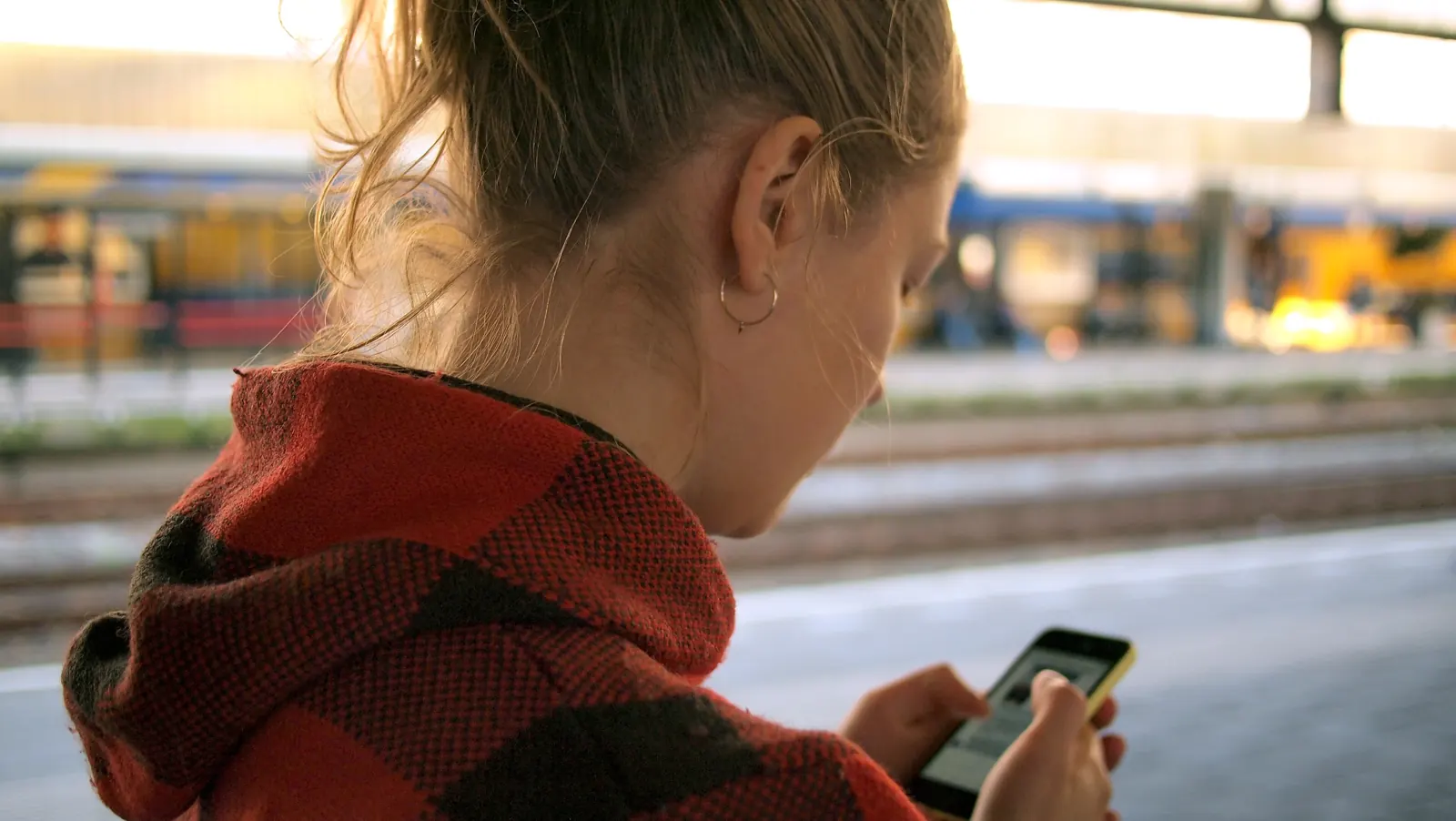 Quelqu’un lit son téléphone dehors, près d’une gare.